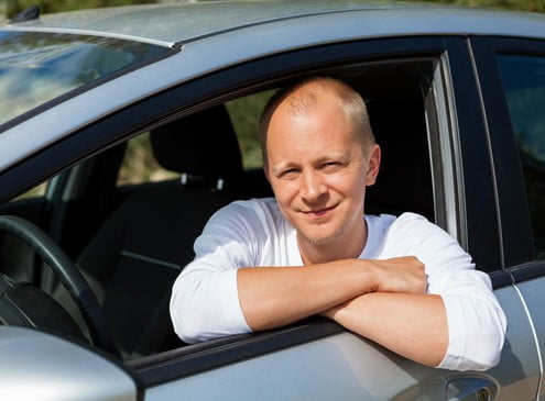 Foto eines Fahrlehrers, der lächelnd aus dem Fenster seines Fahrschulautos schaut